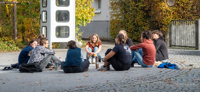 Eine Gruppe von Menschen sitzt draußen im Kreis