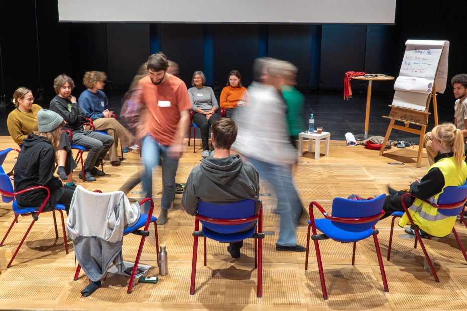 Menschen sitzen im Kreis, manche tanzen